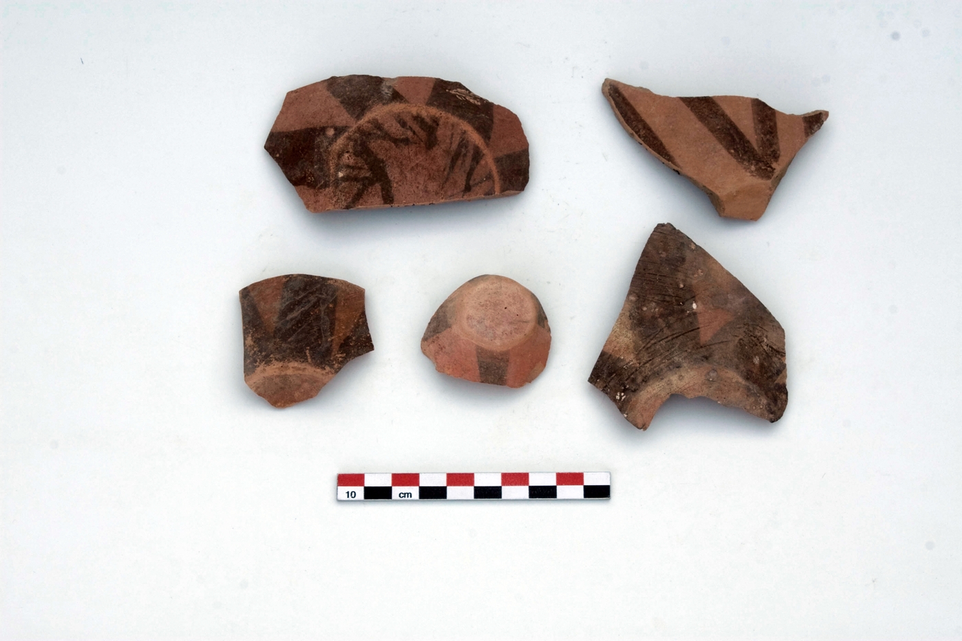Meana Black on Red bases with rays extending upwards from the base. Viewed from the bottom, they present a star-shaped pattern. The edges of the slightly concave bases are heavily worn, indicating that the vessels have been moved around a lot during their use.